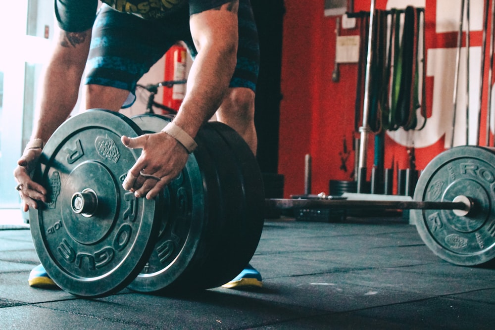 man placing weight plate on barbell