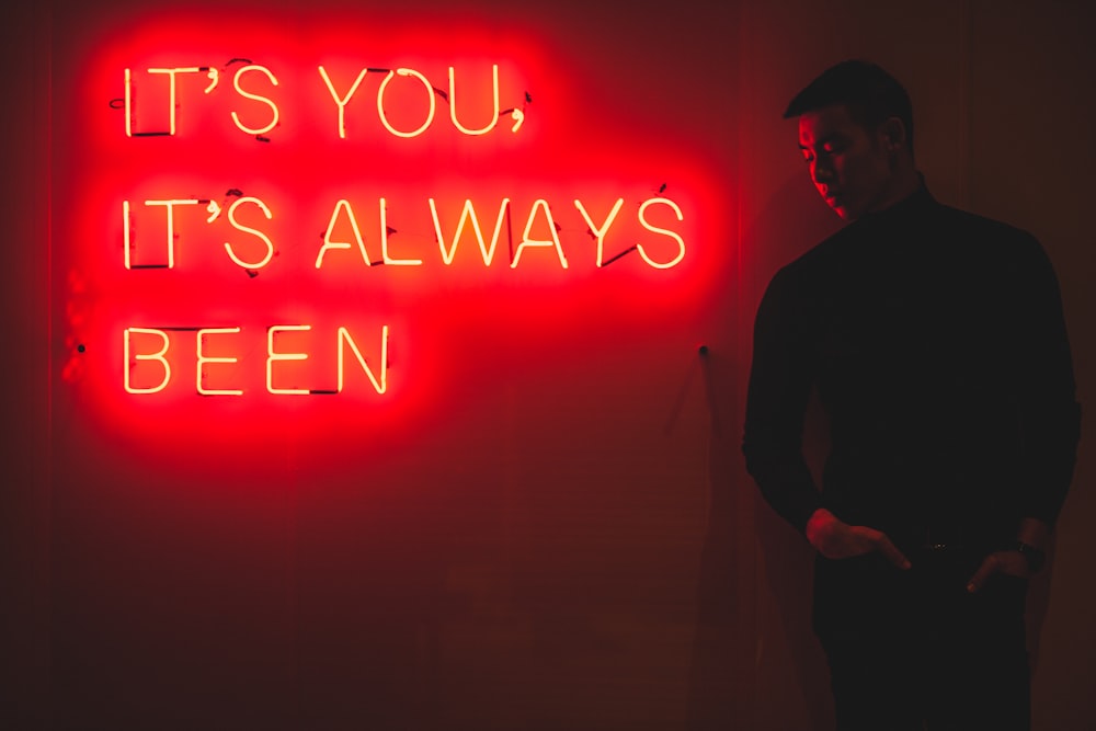 man standing beside red LED sign