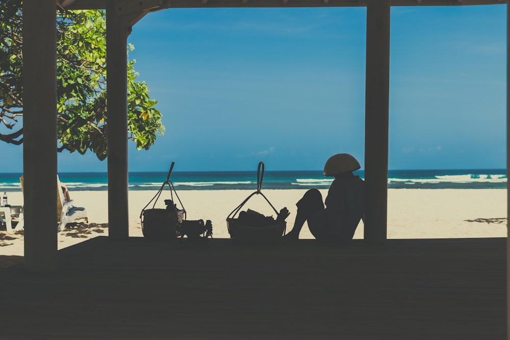 silhouette of person near basket while looking seashore during daytime