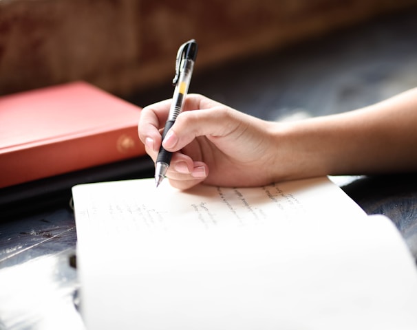 a person writing on a piece of paper with a pen