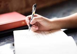 a person writing on a piece of paper with a pen