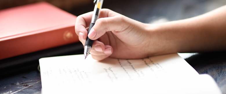 A person writing on a piece of paper with a pen