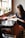 woman sitting in front of black table writing on white book near window