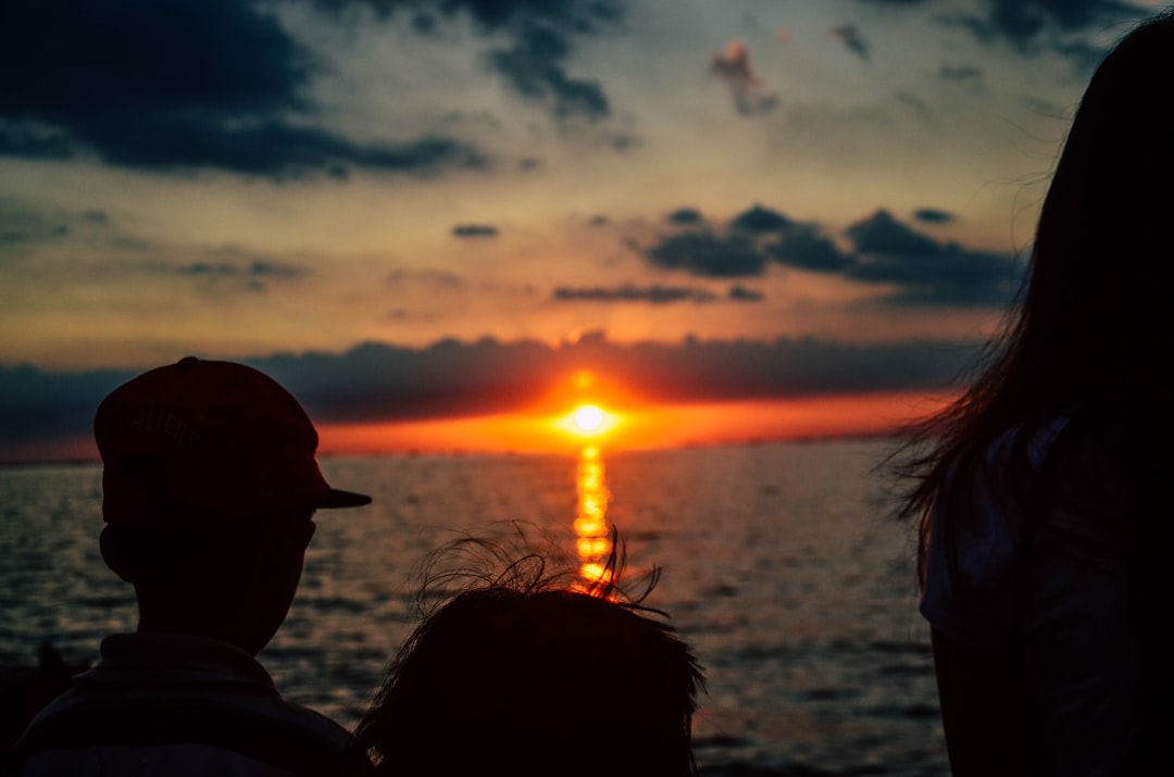 silhouette of children looking on orange sunset above sea