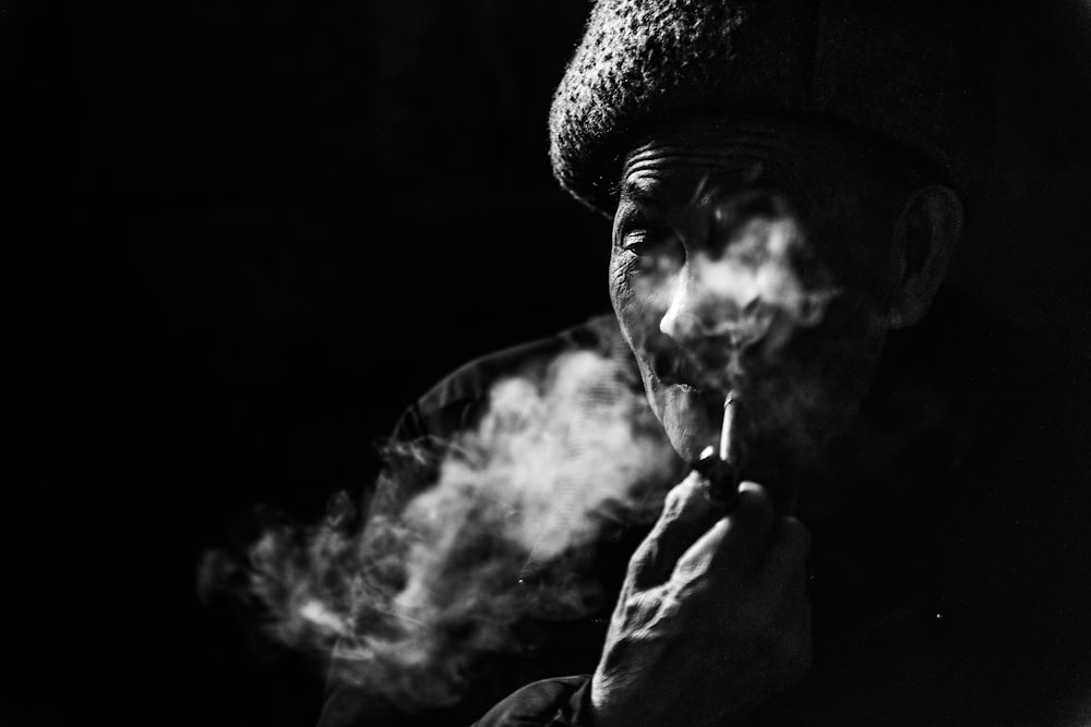 person smoking pipe grayscale photo
