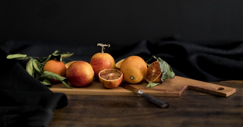 ナイフ付き茶色の木製のまな板にオレンジ色の果物