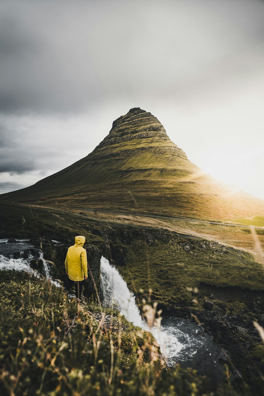 person standing on cliff near waterfalls during daytime