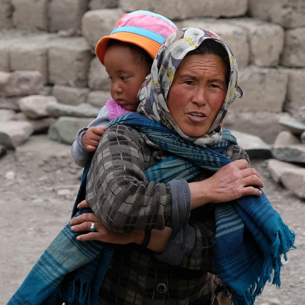 femme portant un foulard tout en portant une fille dans son dos pendant la journée