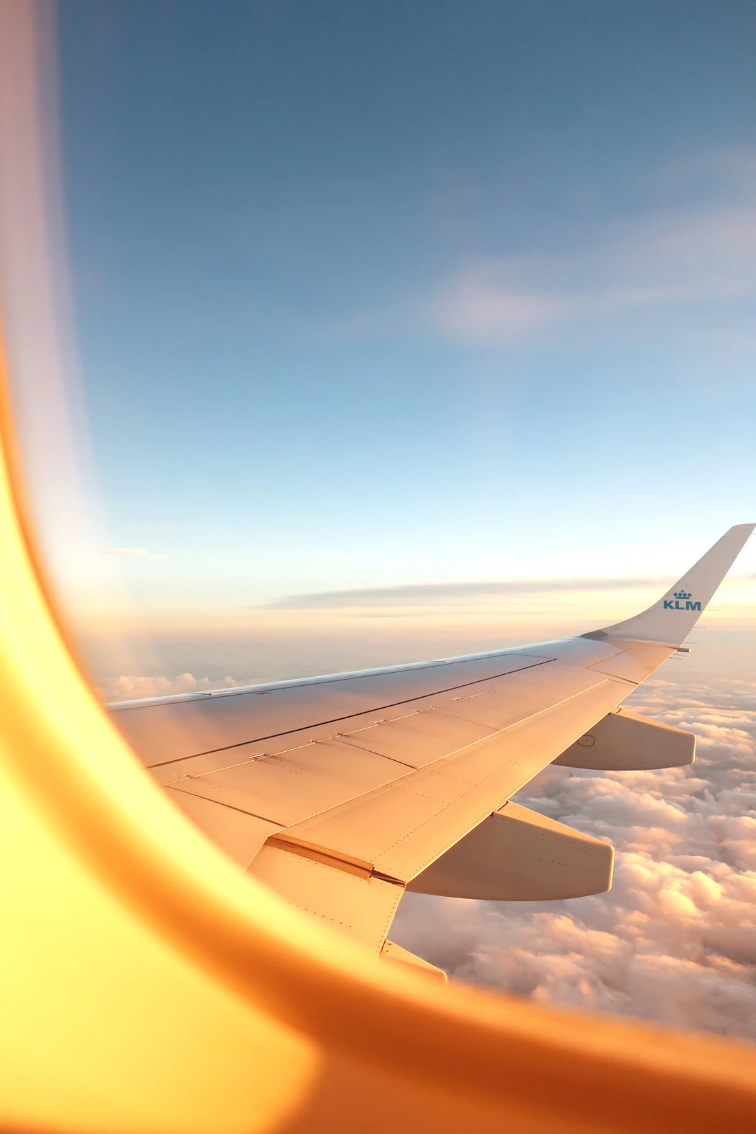 An aircraft wing catching golden light above the clouds