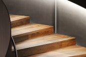 Architectural detail of a bespoke wooden staircase with clean lines and warm ambient lighting.