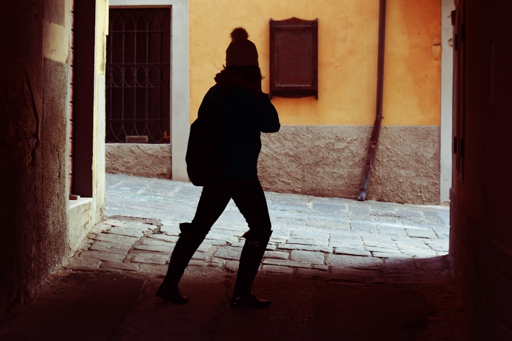 a woman walking down a street next to a yellow building