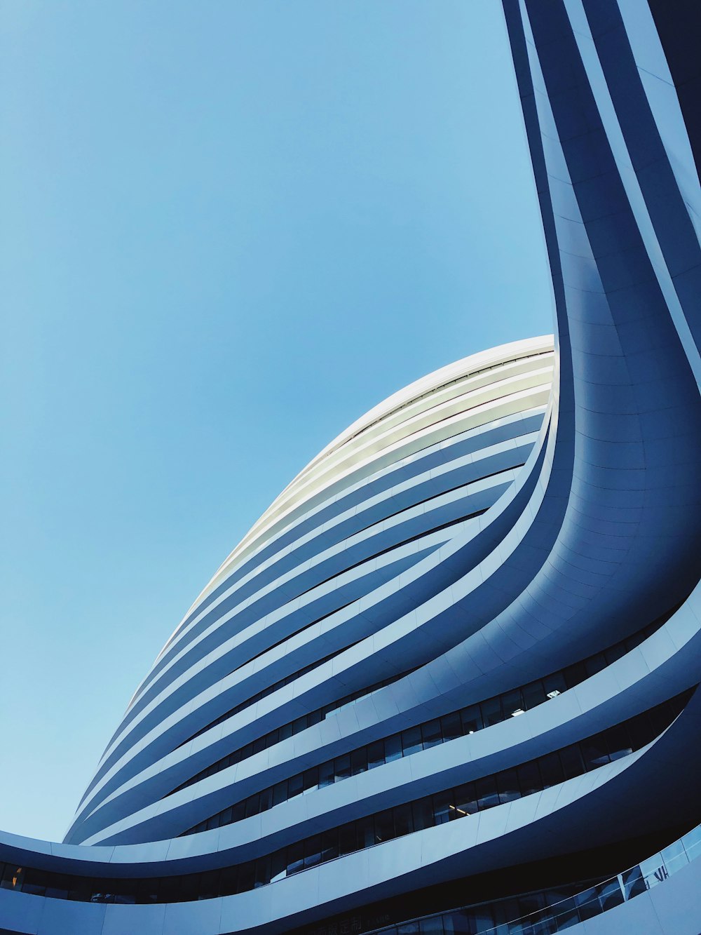 푸른 잔잔한 하늘 아래 고층 빌딩의 모습을 로우 앵글 촬영