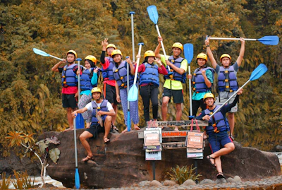 A cheerful group preparing for a canyoning adventure with helmets and wetsuits.