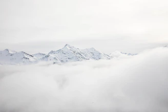 mountain range covered with snow and clouds at daytime