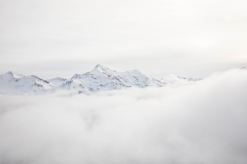 mountain range covered with snow and clouds at daytime