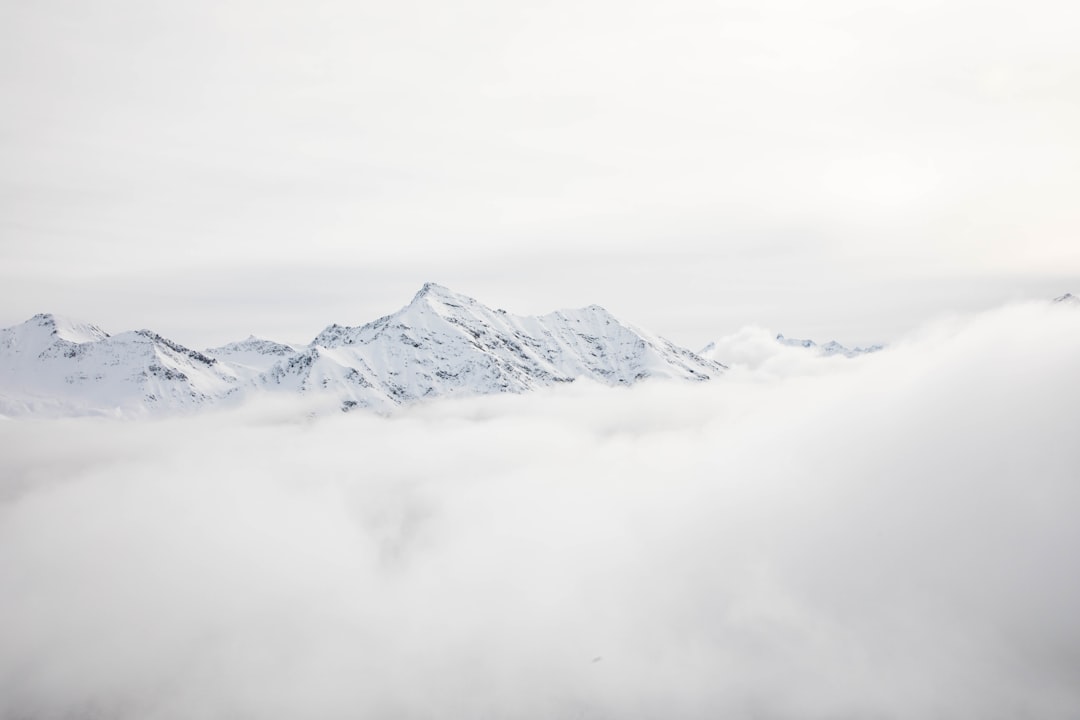 mountain range covered with snow and clouds at daytime