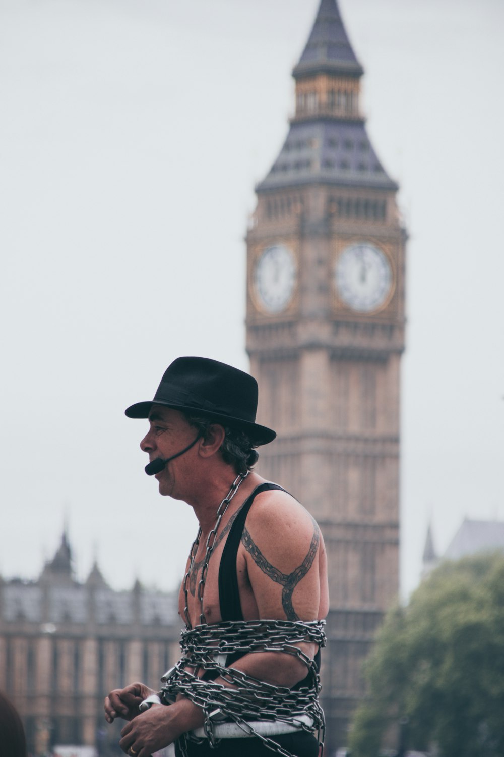 Foto a fuoco selettiva di un uomo coperto di catena con microfono con vista sul Big Ben