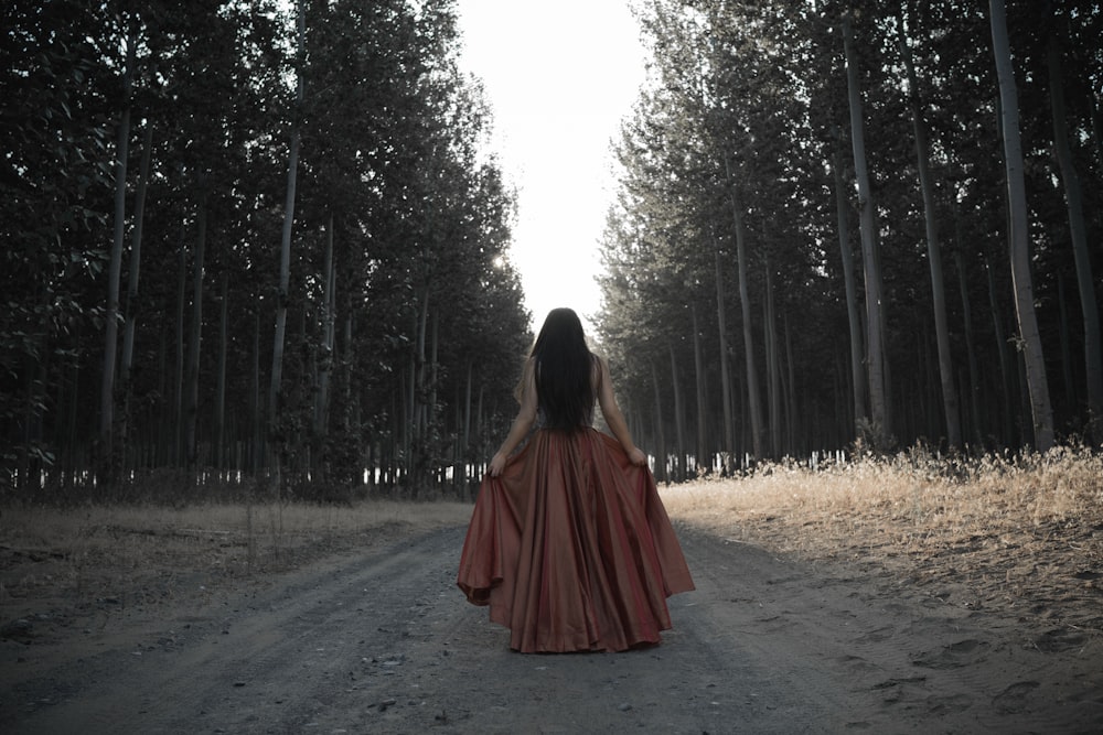 Frau hält ihr braunes Kleid mitten im Wald