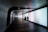 A futuristic, curved hallway with illuminated walls displays a gradient of colors. Two people walk together in silhouette along the dimly lit corridor, creating a sense of mystery and intrigue. The ceiling features geometric patterns with recessed lighting.