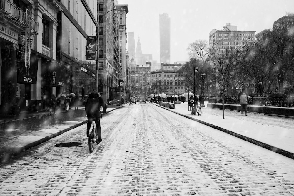 grayscale photo of man riding bicycle on road