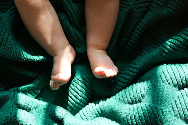 A soft morning light casting gentle shadows over a tiny pair of baby shoes on a wooden floor.