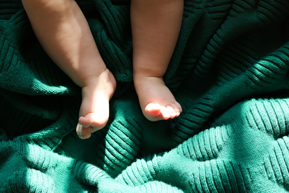 a baby laying on a green blanket on top of a blanket
