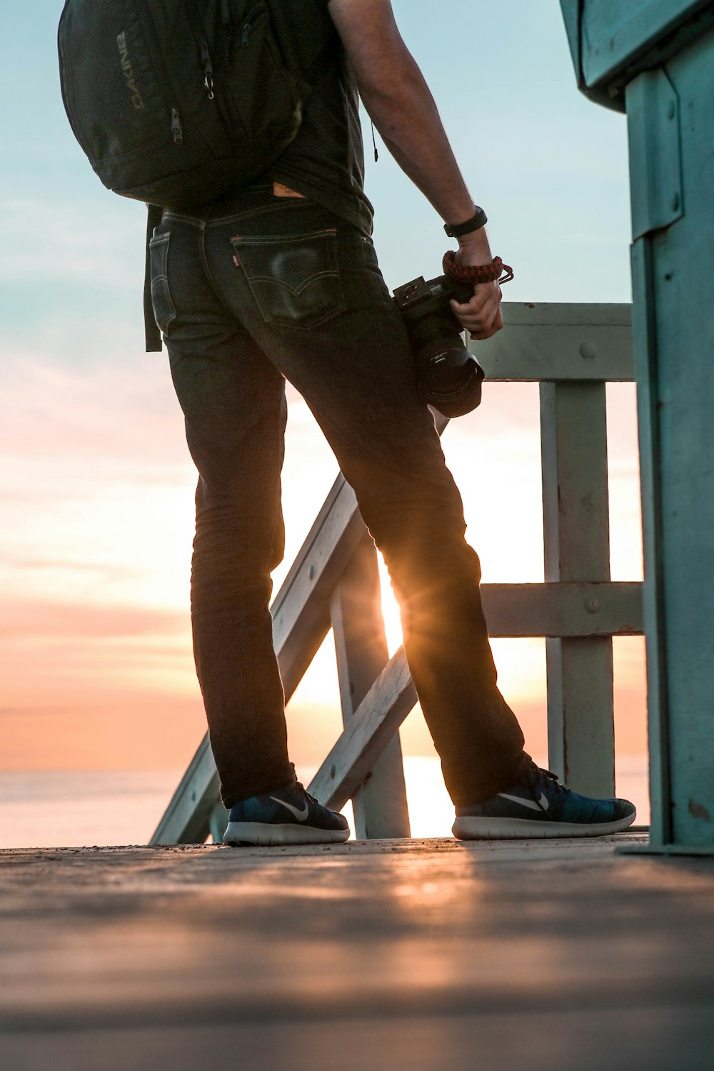 person in black top and jeans holding DSLR camera