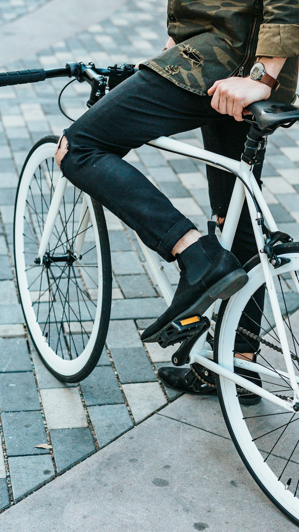 hombre con pantalones negros montando una bicicleta blanca