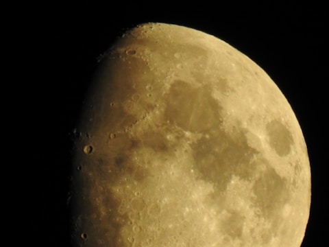 A detailed lunar surface with visible craters and textures, captured under a dark sky.