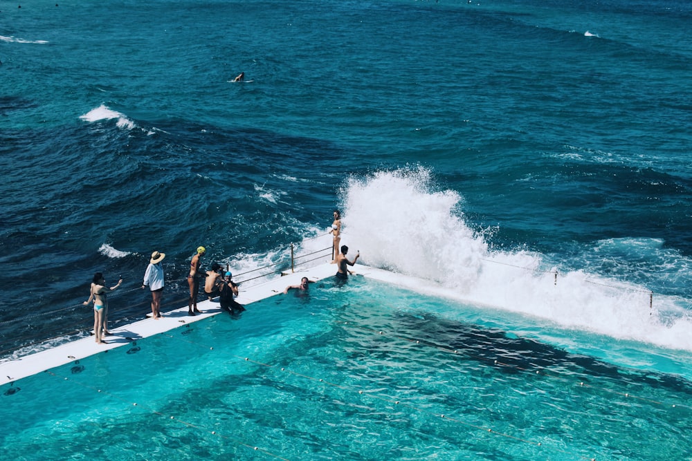 people standing on poolside beside sea during day