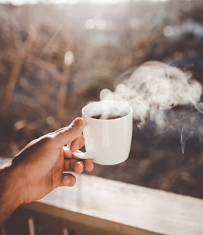 person holding white ceramic cup with hot coffee