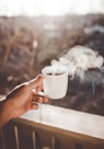 person holding white ceramic cup with hot coffee