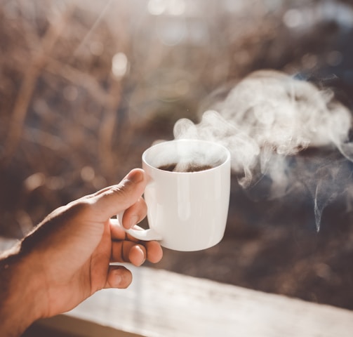 person holding white ceramic cup with hot coffee