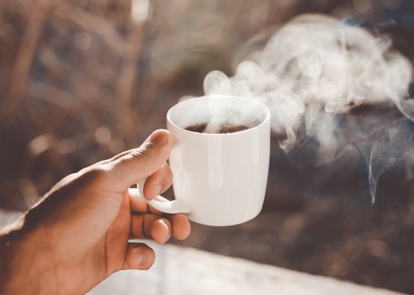 person holding white ceramic cup with hot coffee