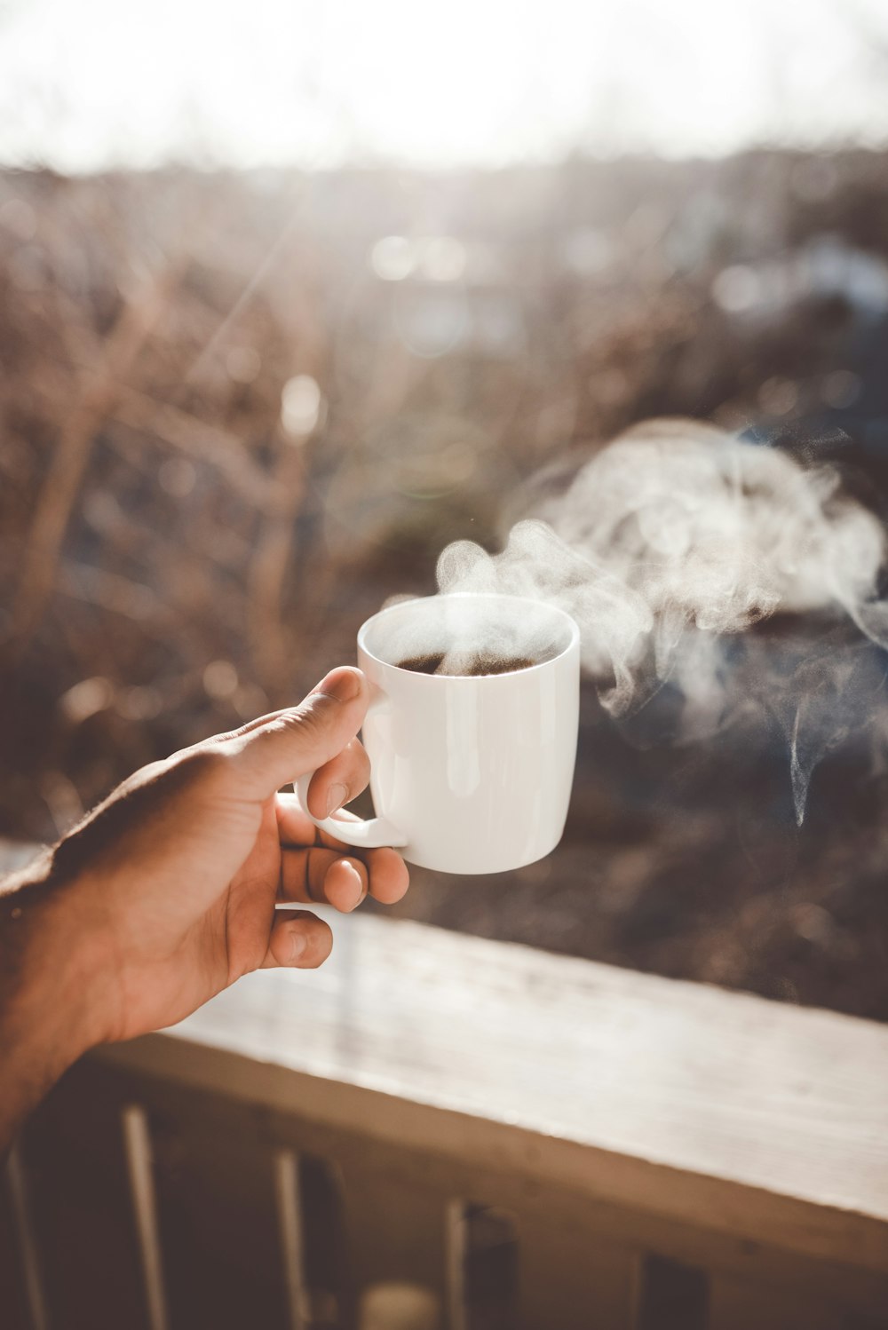 person holding white ceramic cup with hot coffee