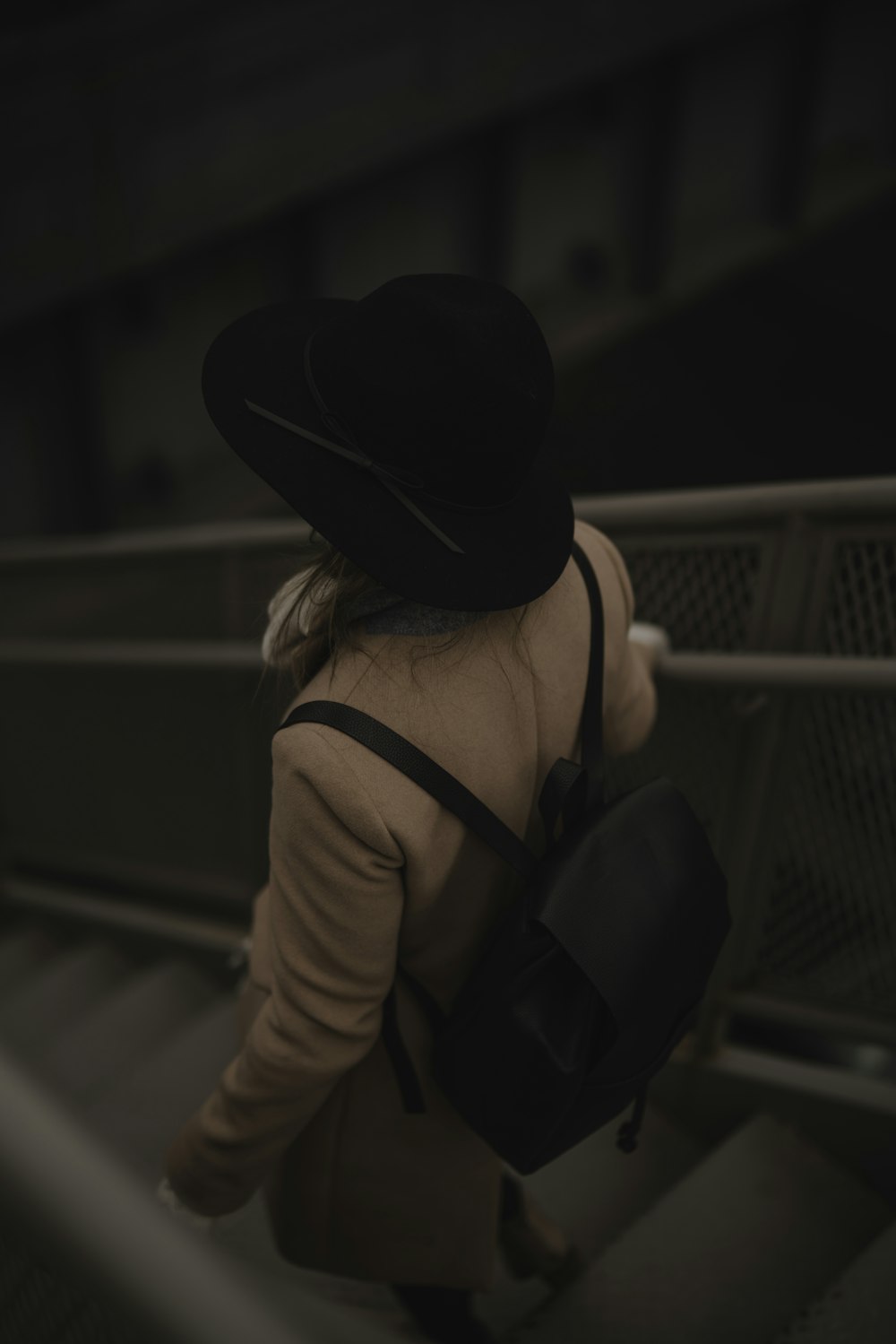 person carrying black backpack while walking downards of stair