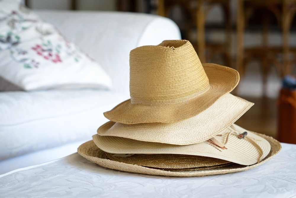 Cinq chapeaux de paille brune gigogne sur textile blanc