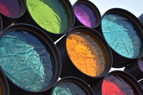 A series of circular, colored translucent panels are arranged, each featuring different hues such as green, yellow, blue, and purple. The light filters through each one, creating vivid reflections. The textured surfaces give off a crinkled appearance, enhancing the visual interest.
