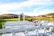 Elegant outdoor wedding ceremony framed by lush green hills and clear skies.
