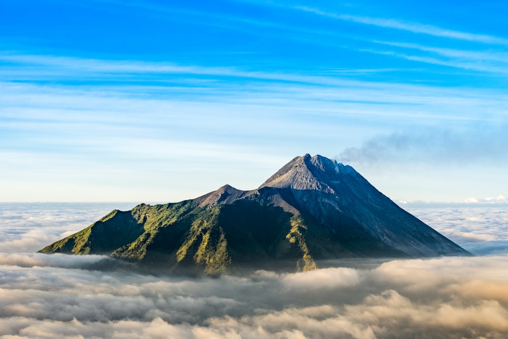 mountain range covered with clouds under blue sky at daytime