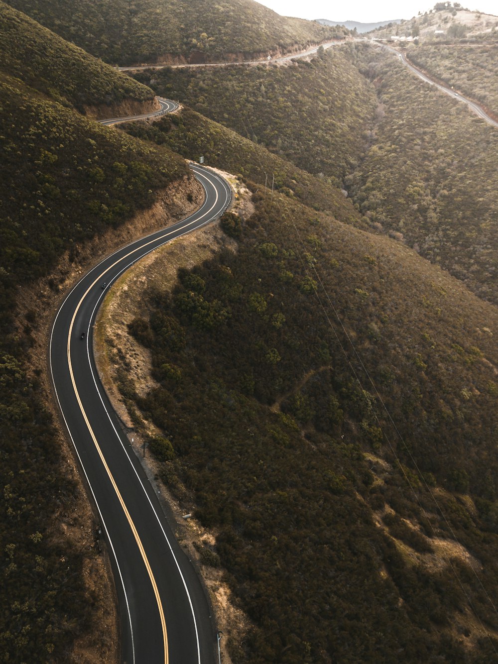 aerial photo of black concrete top road near green mountains