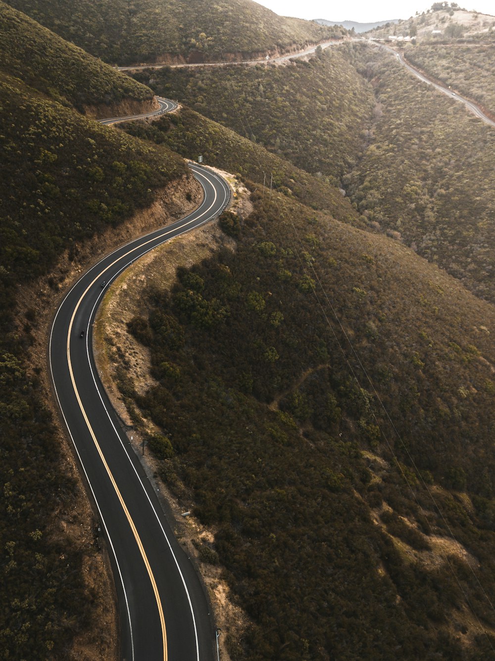 Foto aérea de la carretera superior de hormigón negro cerca de las montañas verdes