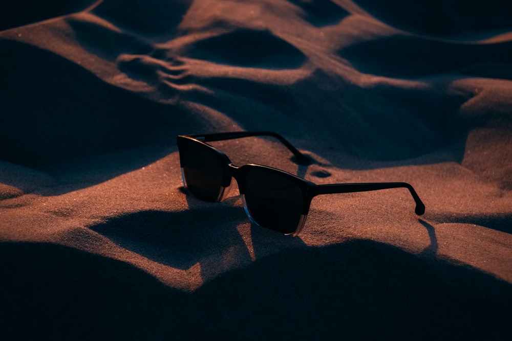 silhouette photography of black framed sunglasses on sand