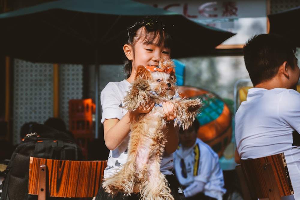 girl standing holding long-coat brown puppy