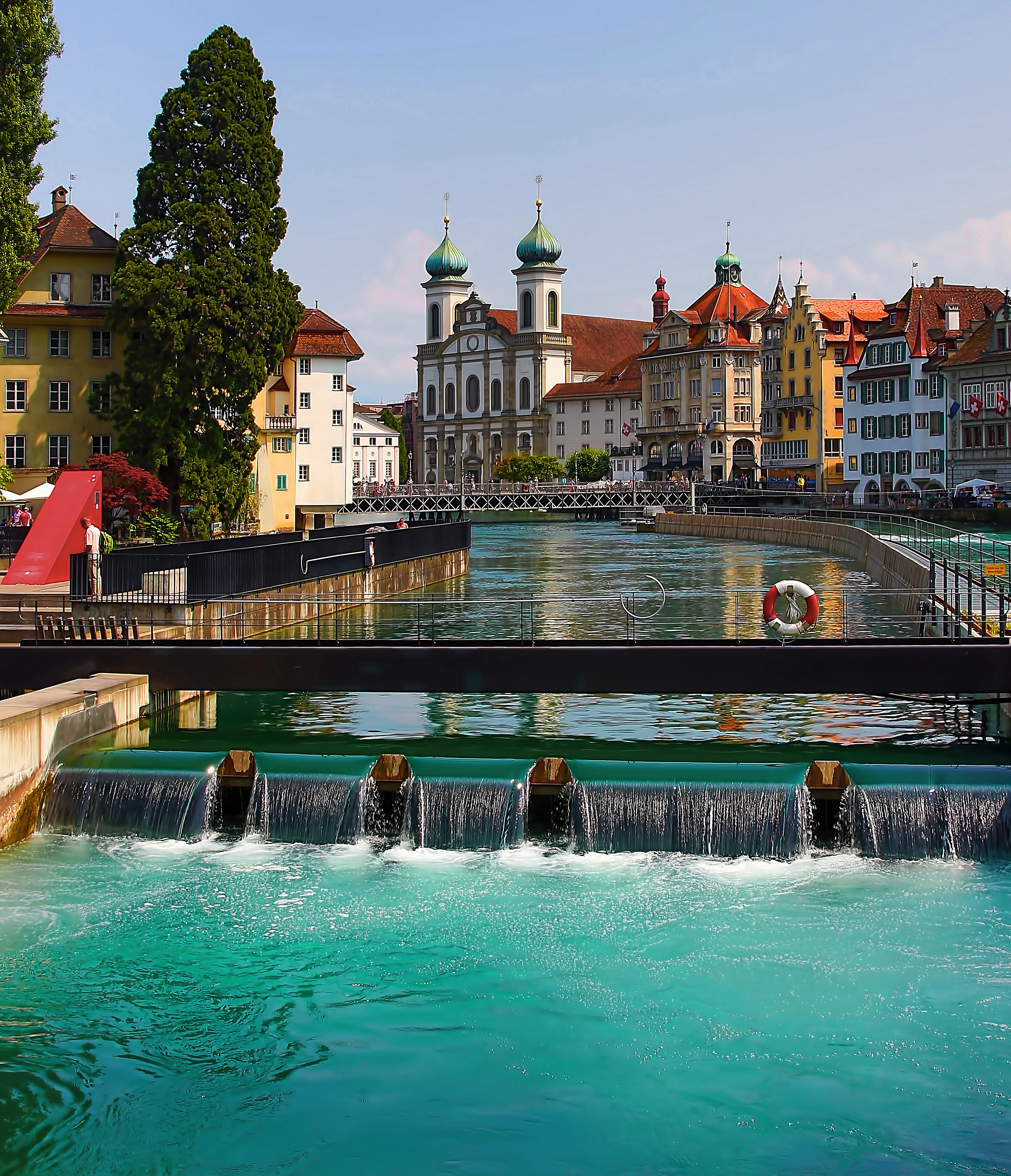 The white towers of the Jesuit Church rising above the weirs of the Reuss river in Lucerne's old town