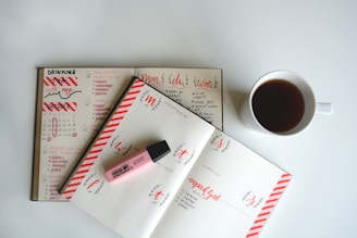 white ceramic teacup with beverage beside pink marker on pritner p pe