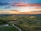 road between green grass field near mountains under blue and brown sky at golden hour