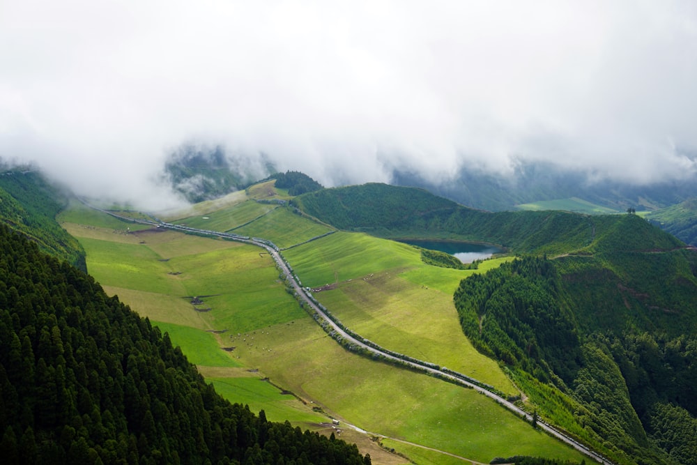 estrada entre campo de grama verde perto de montanhas sob o céu branco durante o dia