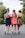 three women wearing red, brown, and blue dresses walking on concrete road during daytime