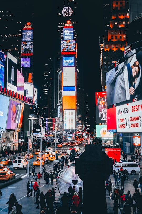 people walking on street surrounded by high buildings during nighttime in Theater District United States